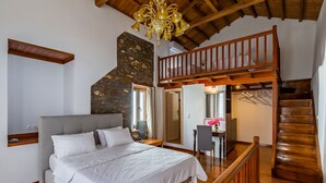 Un dormitorio con una cama, una escalera de madera y una pared de piedra.
