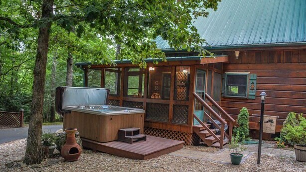 A rustic cabin with a hot tub, wooden deck, and a staircase leading to the entrance. - Chasing Rainbows (Mineral Bluff)