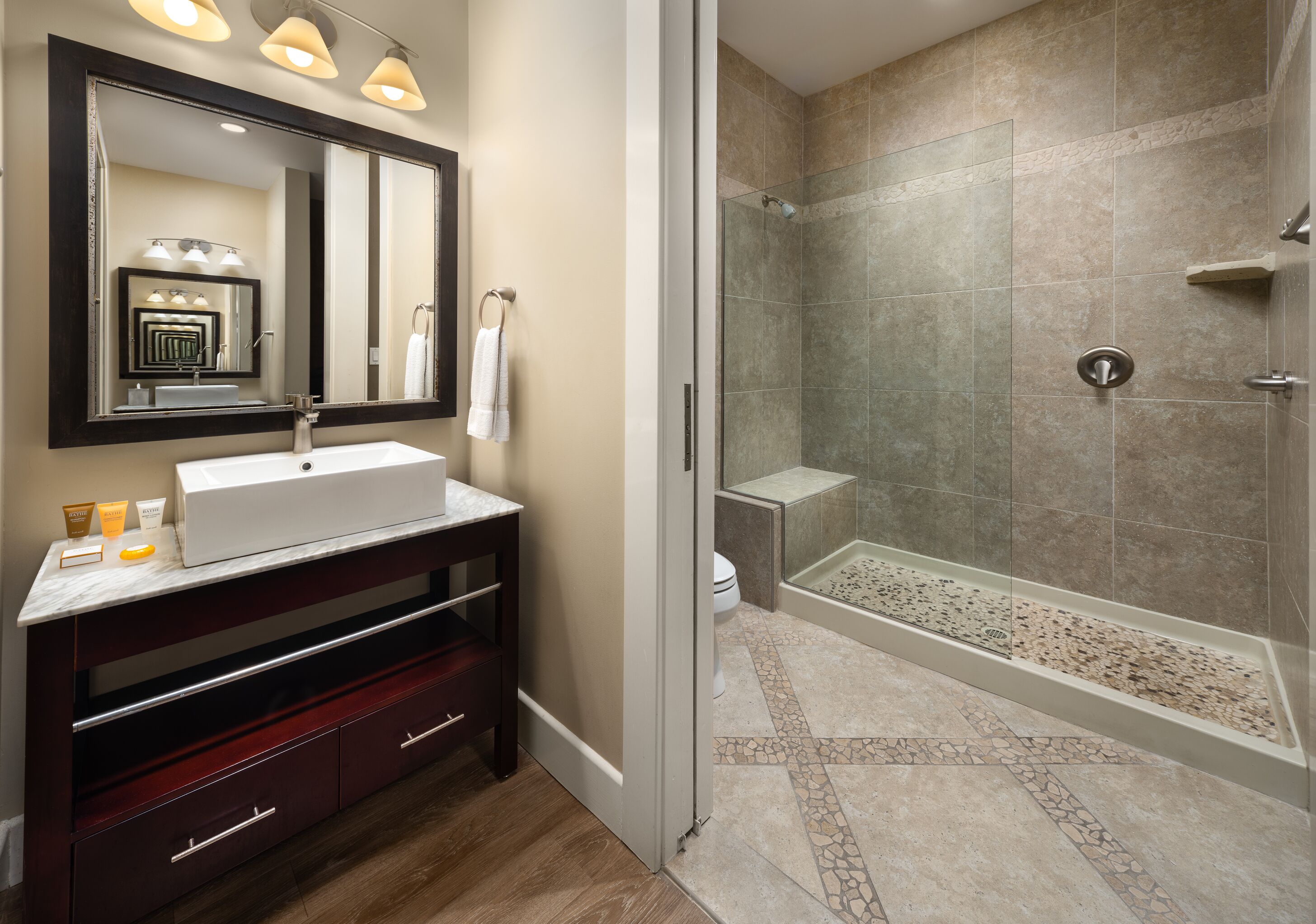A modern bathroom with a large mirror, vanity, and a walk-in shower.