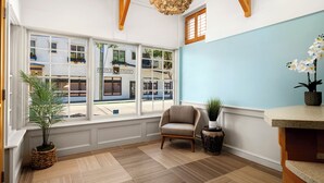Ein Zimmer mit großen Fenstern, einem Sessel, einem Blumentopf und einem außergewöhnlichen Chandelier.