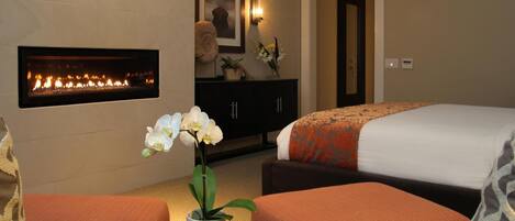 A hotel room with a fireplace, a bed, a sofa, and a coffee table.