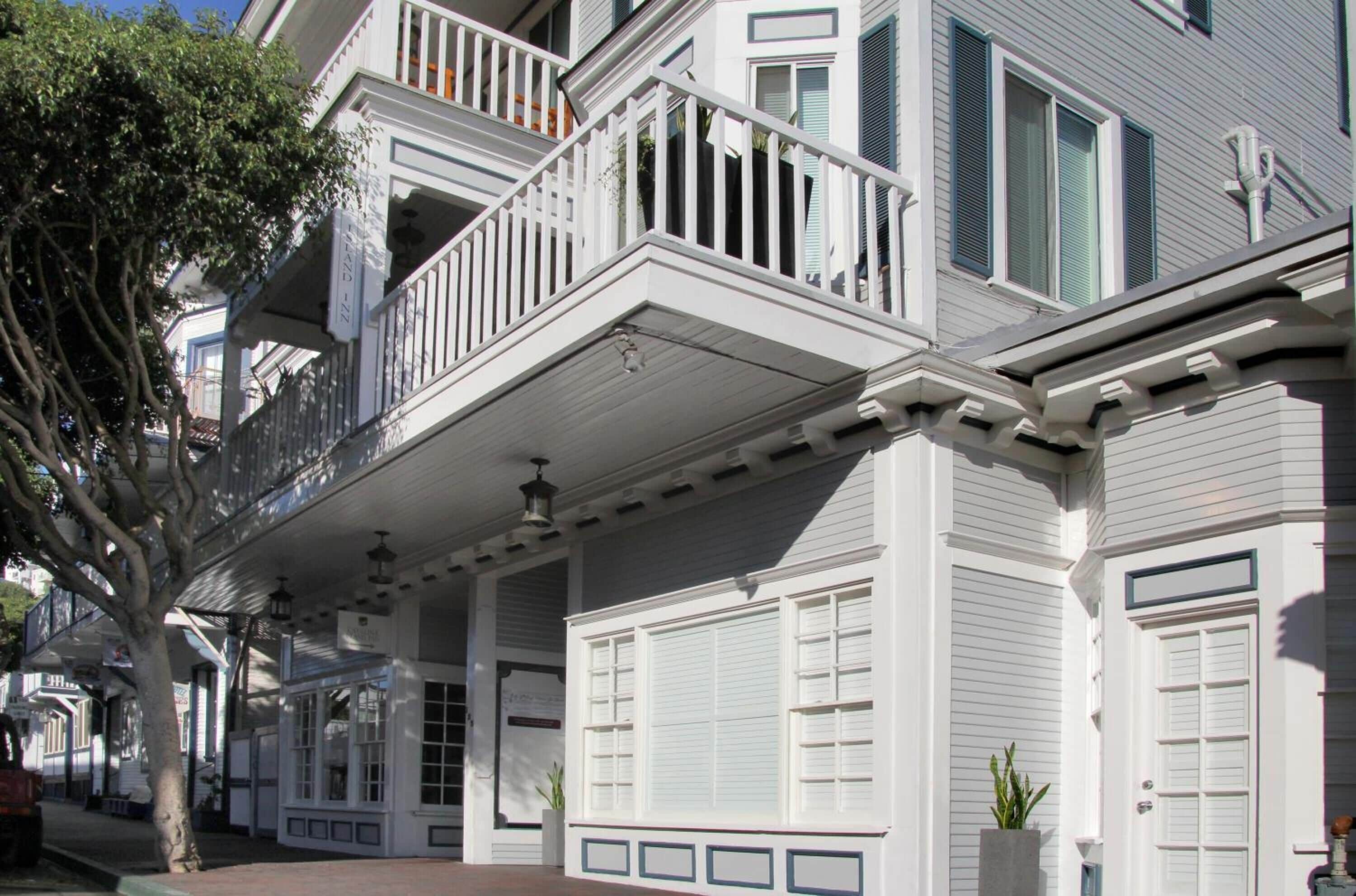A white building with a balcony, a covered porch, and a large window.