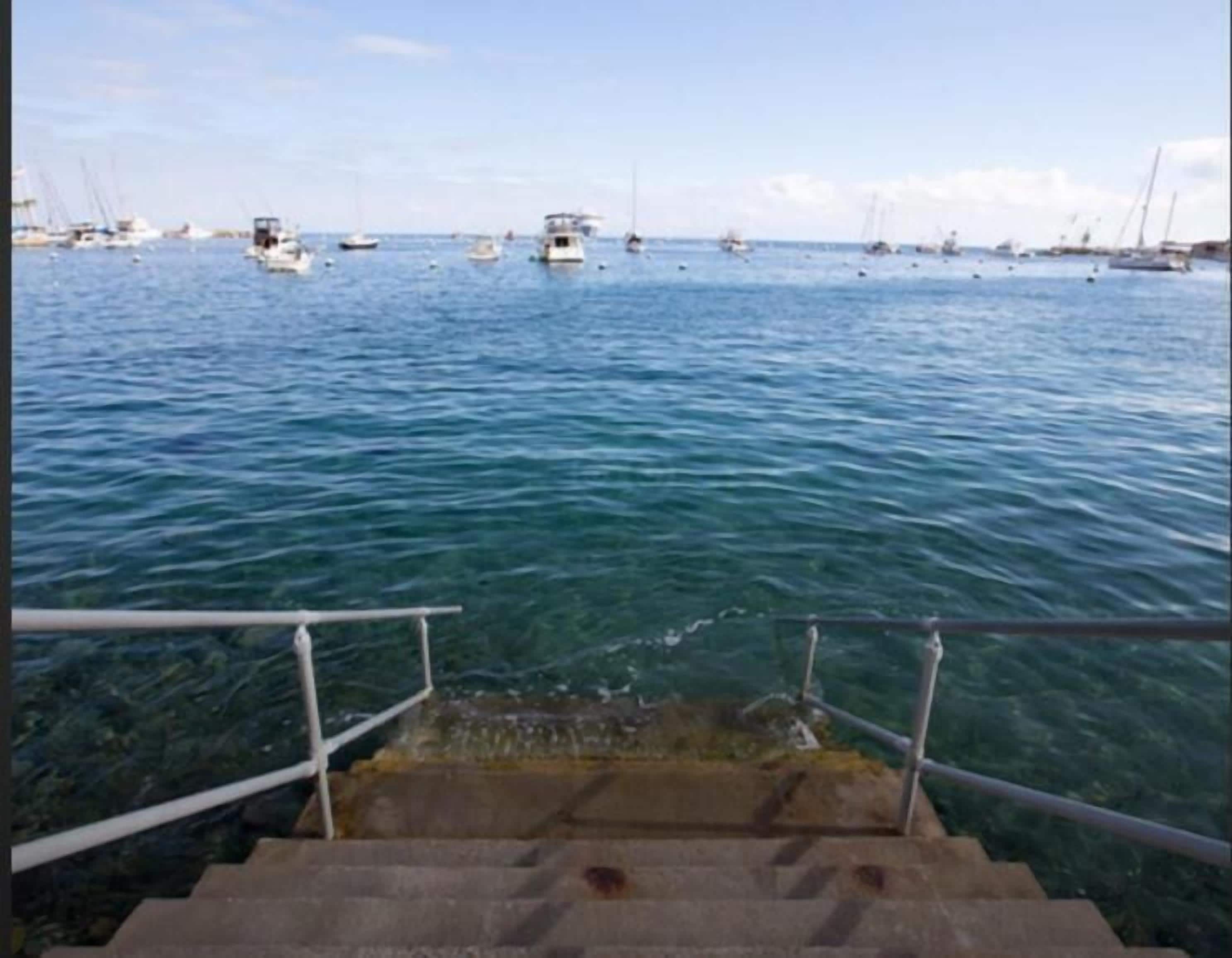 Une vue sur un port, avec des bateaux et un escalier qui descend vers l’eau.