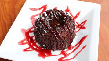 A chocolate lava cake on a white plate with red syrup.
