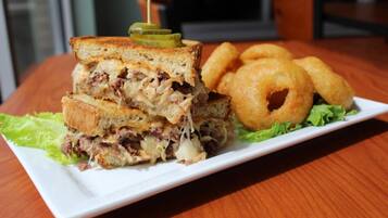 A sandwich with a toothpick, accompanied by onion rings and lettuce on a plate.