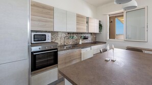 Une cuisine moderne dotée d’appareils électroménagers intégrés, d’un grand îlot central et offrant une vue sur l’extérieur.