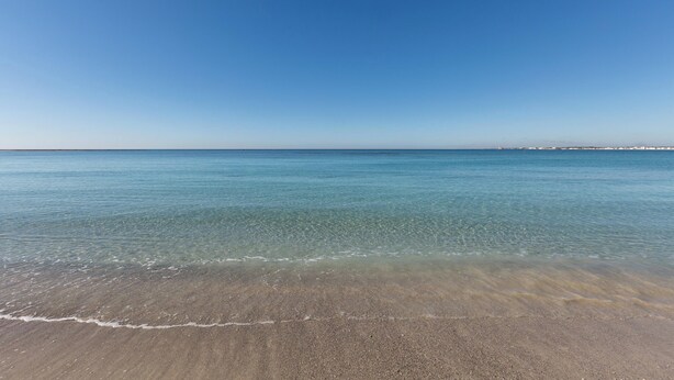 Une plage à l’eau claire et au vaste rivage sablonneux.