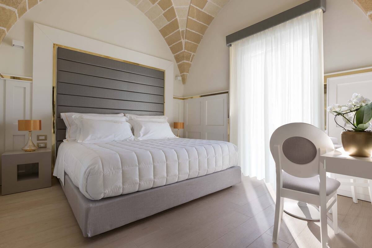 A modern bedroom with a large bed, a desk, and a chair.