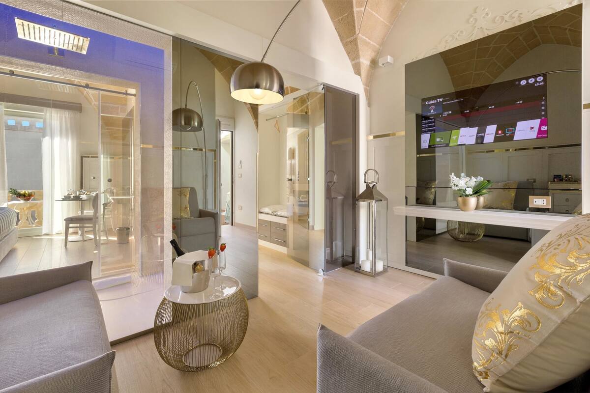 A modern living room with a sofa, a round coffee table, and a TV displaying a guide channel.