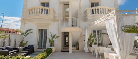 A two-story building with a central balcony, outdoor seating area, and a covered patio.