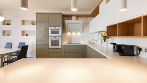 A modern kitchen with built-in appliances, a dining area with a table and chairs, and a wooden accent wall. - 1327 Appartamento Spinalonga by Barbarhouse (Gallipoli)