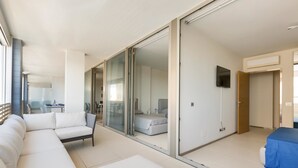 A modern hotel room with a large sliding glass door leading to a balcony, a sofa, a bed, and a small table. - 1327 Appartamento Spinalonga by Barbarhouse (Gallipoli)