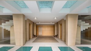 A modern hotel lobby with a central staircase, glass walls, and a patterned floor. - 1327 Appartamento Spinalonga by Barbarhouse (Gallipoli)