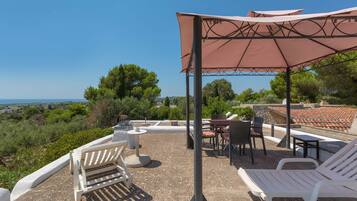 Une terrasse extérieure dotée d’une pergola, de sièges et offrant une vue sur la mer.