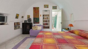 A bedroom with a large bed, a TV, a bookshelf, and a door leading to another room. - Pajara Annelies (Salve)