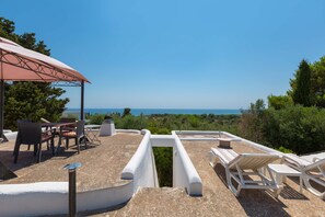 Una terrazza sul tetto con posti a sedere all'aperto, un pergolato e vista sul mare.