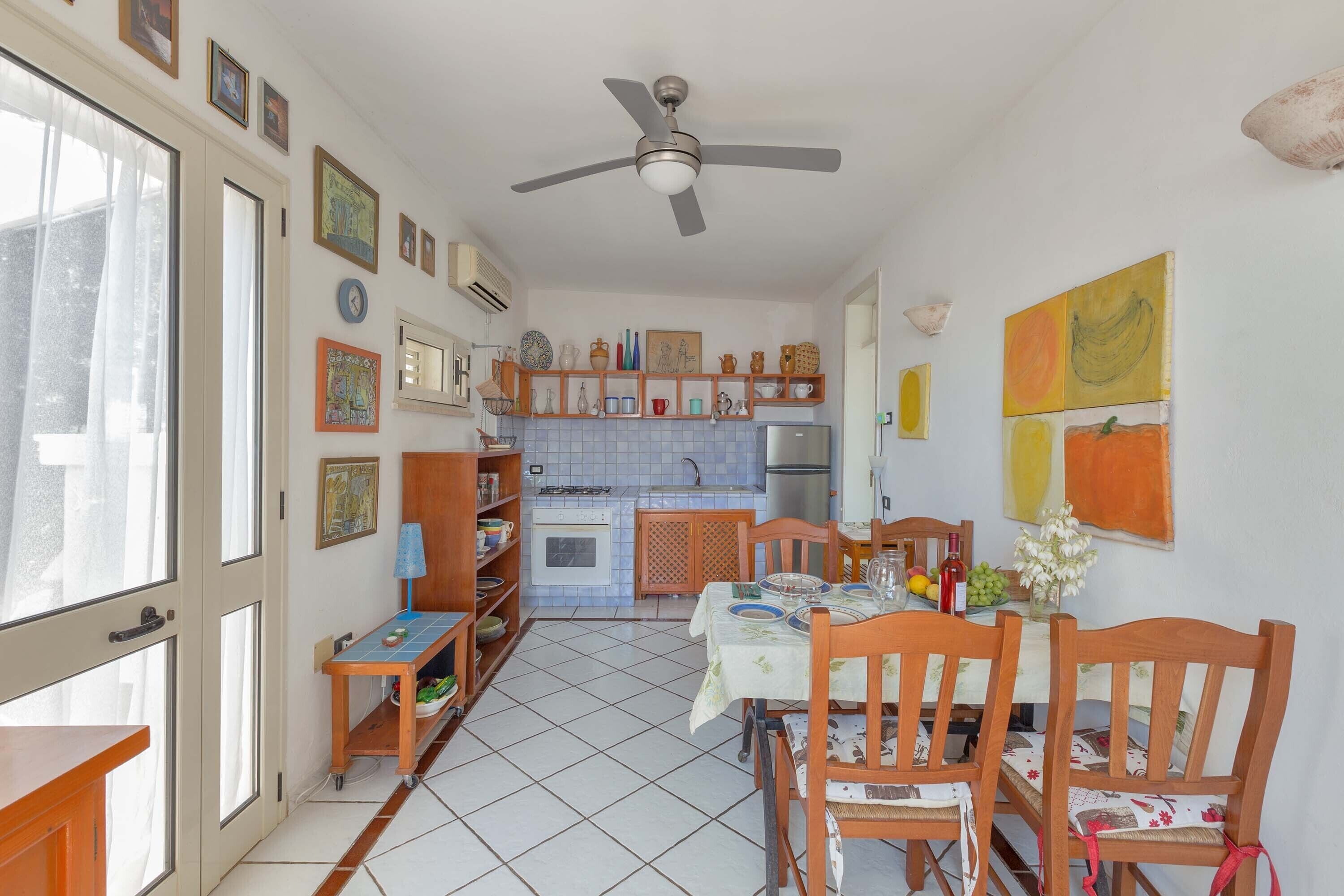 Cucina con zona pranzo, dotata di ventilatore a soffitto, pavimento piastrellato e diversi elettrodomestici.