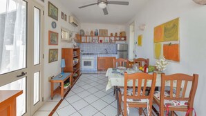 A kitchen with a dining area, featuring a ceiling fan, tiled floor, and various kitchen appliances. - Pajara Annelies (Salve)