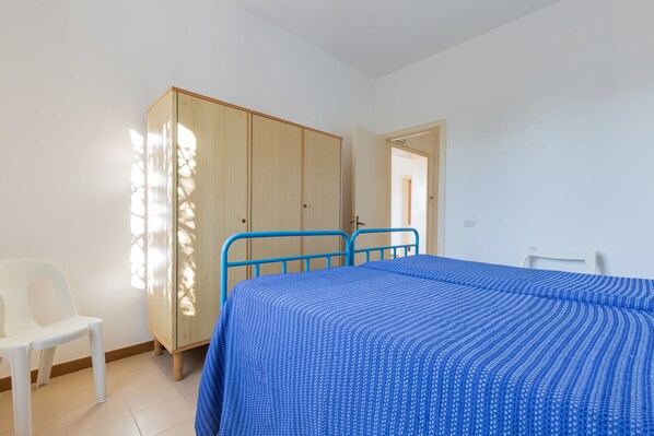 Un dormitorio con una cama, un armario y una silla.