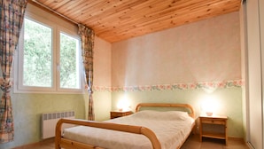 Ein hölzernes Bett in einem Raum mit zwei Nachttischlampen, einem Heizkörper und einem Fenster mit Vorhängen.