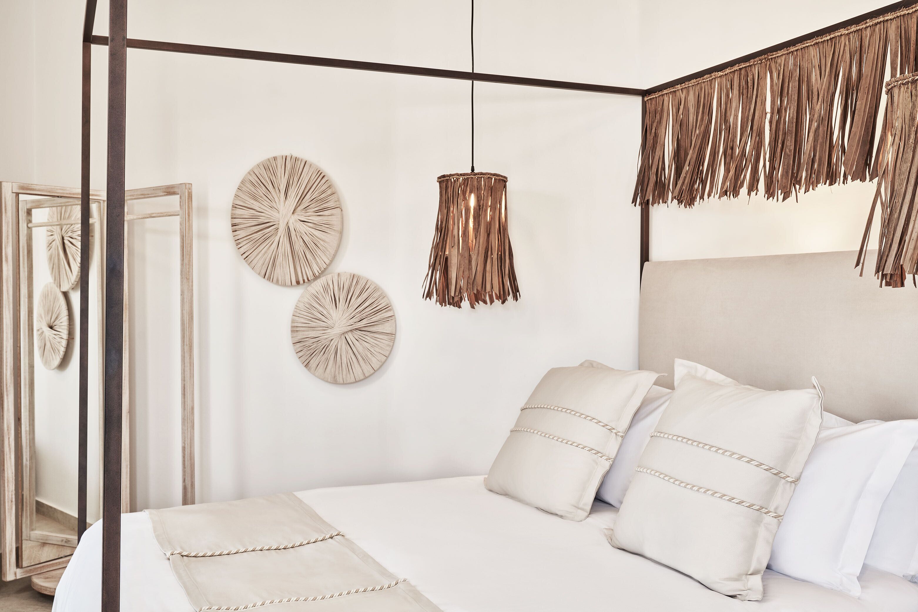 A bedroom with a bed, decorative wall art, and a unique hanging light fixture.