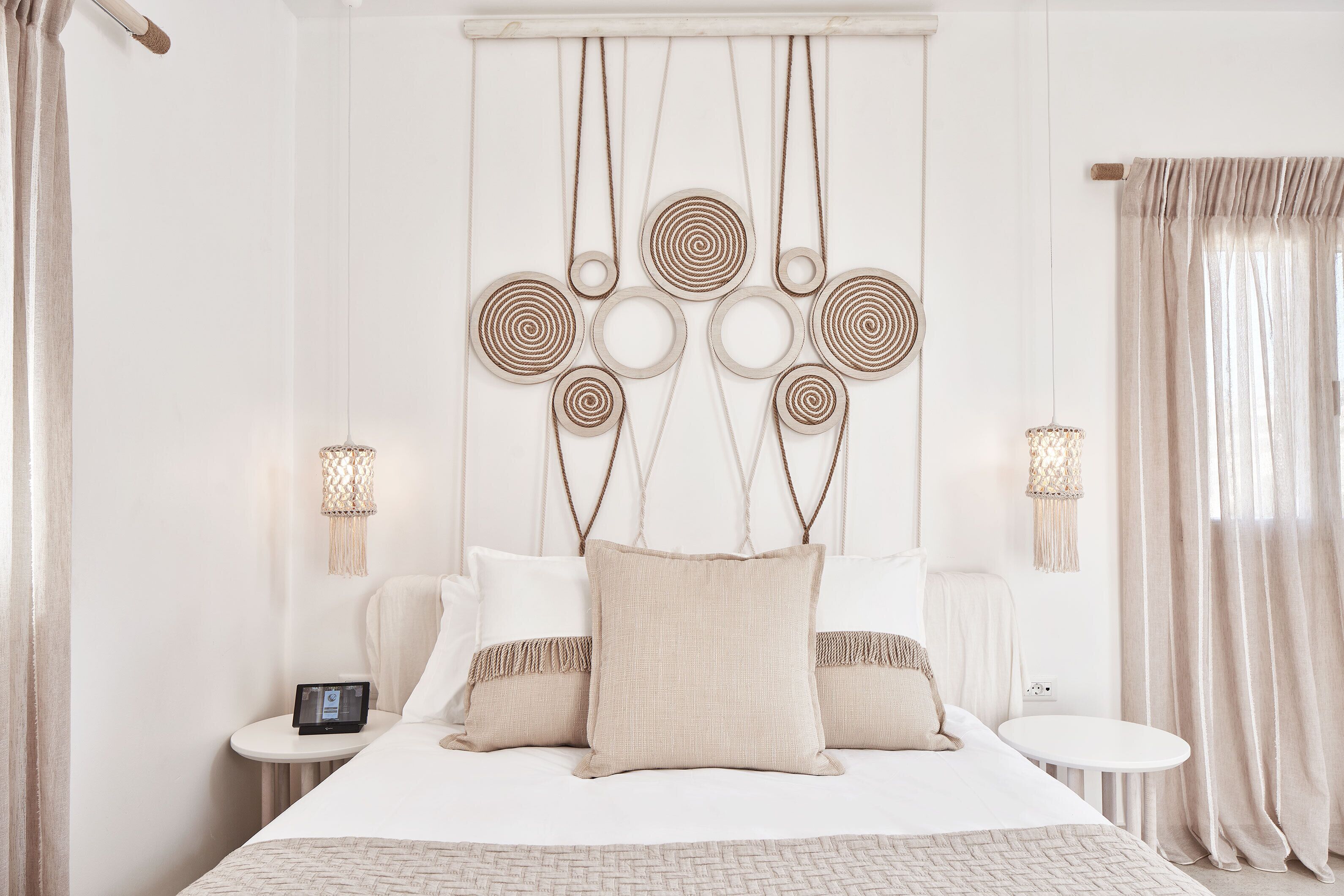 A neatly arranged bedroom with a large bed, bedside tables, and a wall-mounted light fixture.