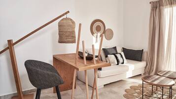 A modern living room with a wooden dining table, a black woven chair, a white sofa, and a wooden floor lamp.