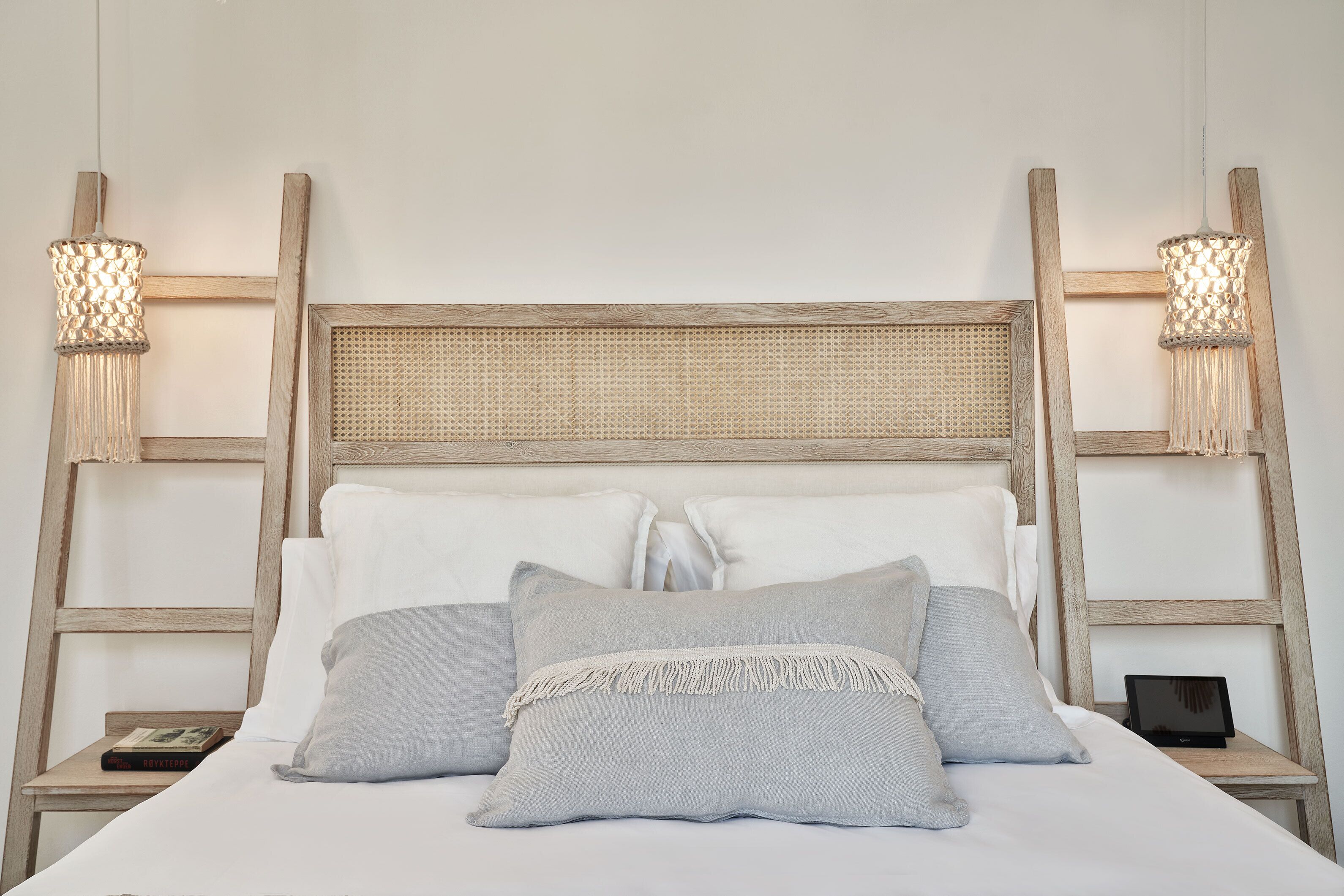 A bed with a wooden headboard, two bedside tables, and two wall-mounted lamps.