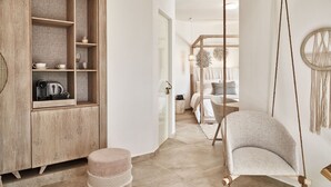 A modern interior with a wooden cabinet, a hanging chair, and a round wall decoration. - Volcano Luxury Suites Milos - Adults Only (Milos)