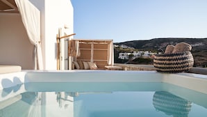 A pool area with a clear view of the surrounding landscape, a wicker chair, and a small table. - Volcano Luxury Suites Milos - Adults Only (Milos)