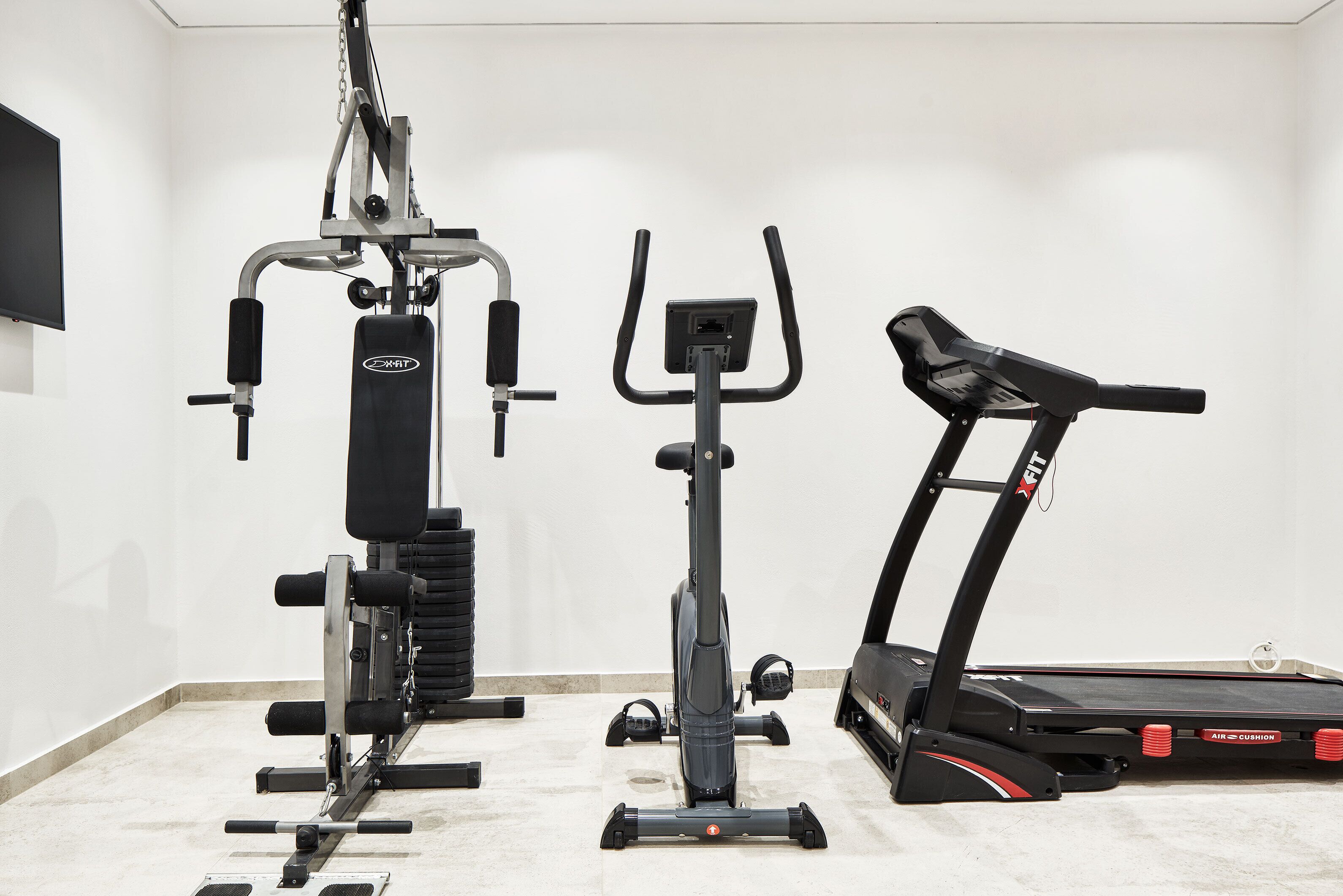 A home gym with a stationary bike, elliptical, and treadmill.