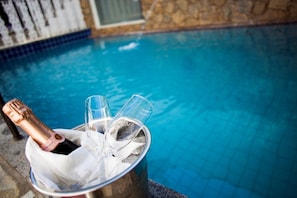 A poolside setting with a bucket containing a bottle of champagne and glasses. - Pousada do Largo (Tiradentes)