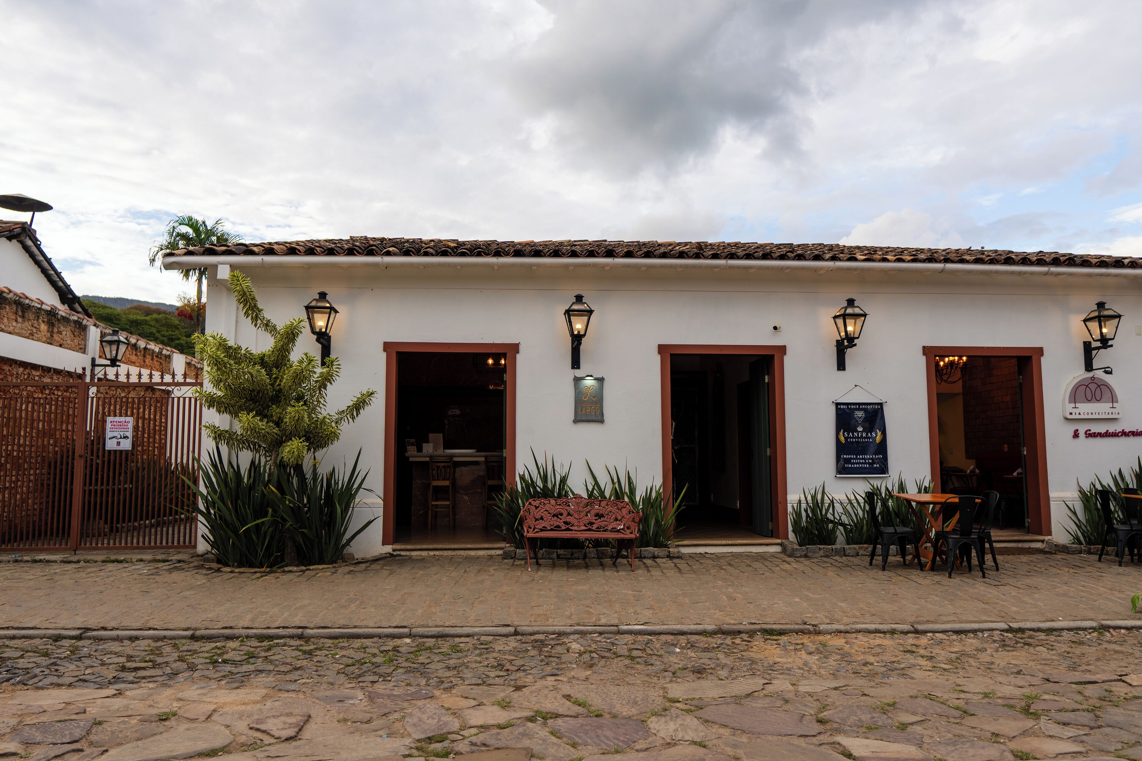 A building with a tiled roof, multiple doors, and outdoor seating.