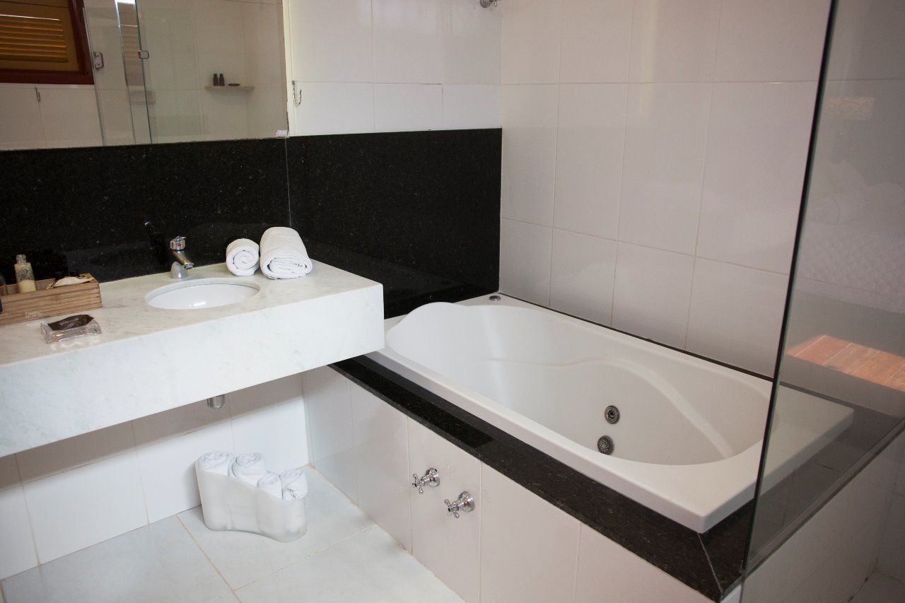 A modern bathroom with a white sink, a large bathtub, and a black countertop.