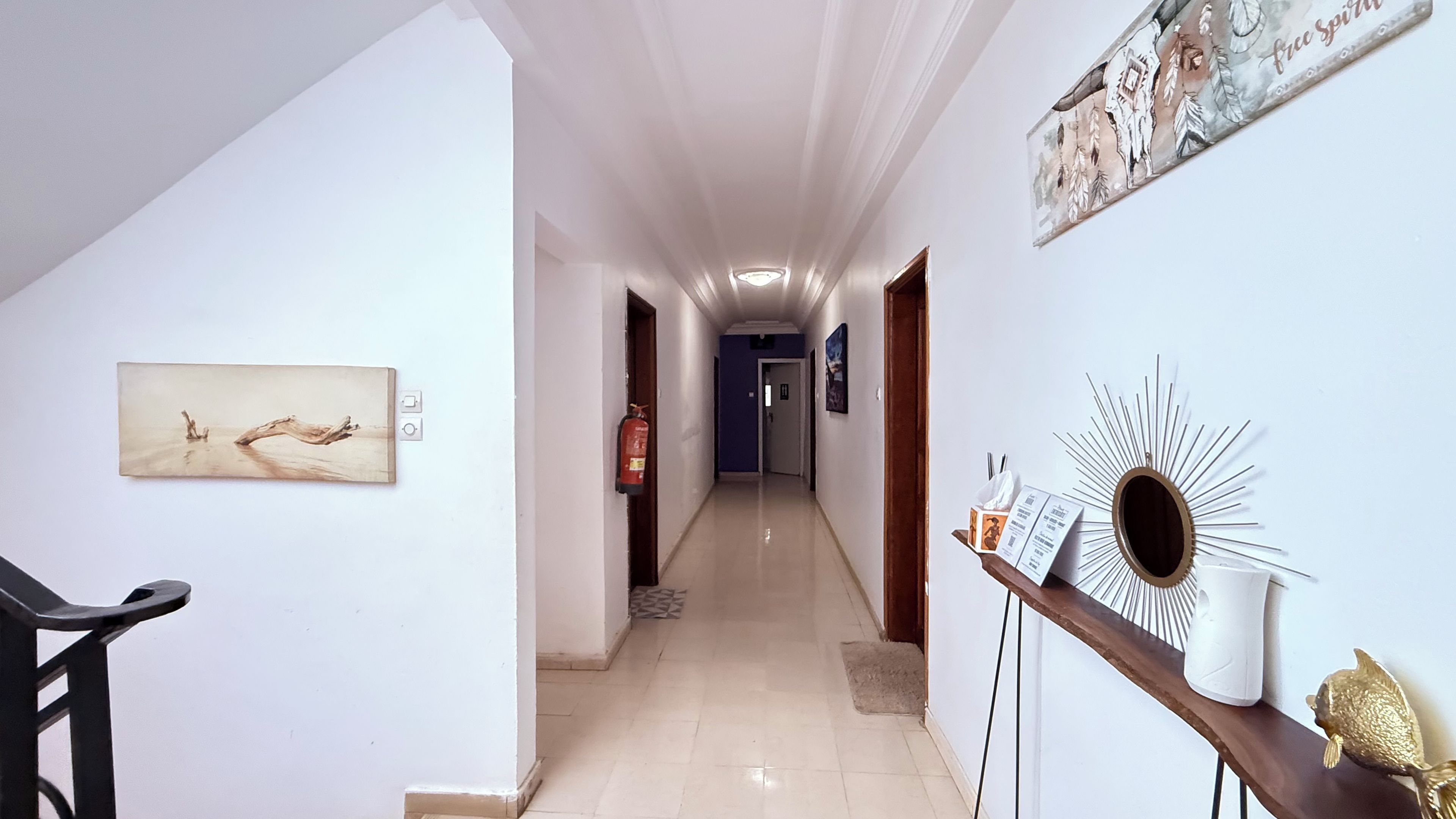 A hallway with a fire extinguisher, a framed picture, and a decorative mirror.