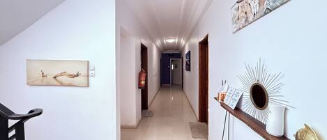 A hallway with a fire extinguisher, a framed picture, and a decorative mirror.