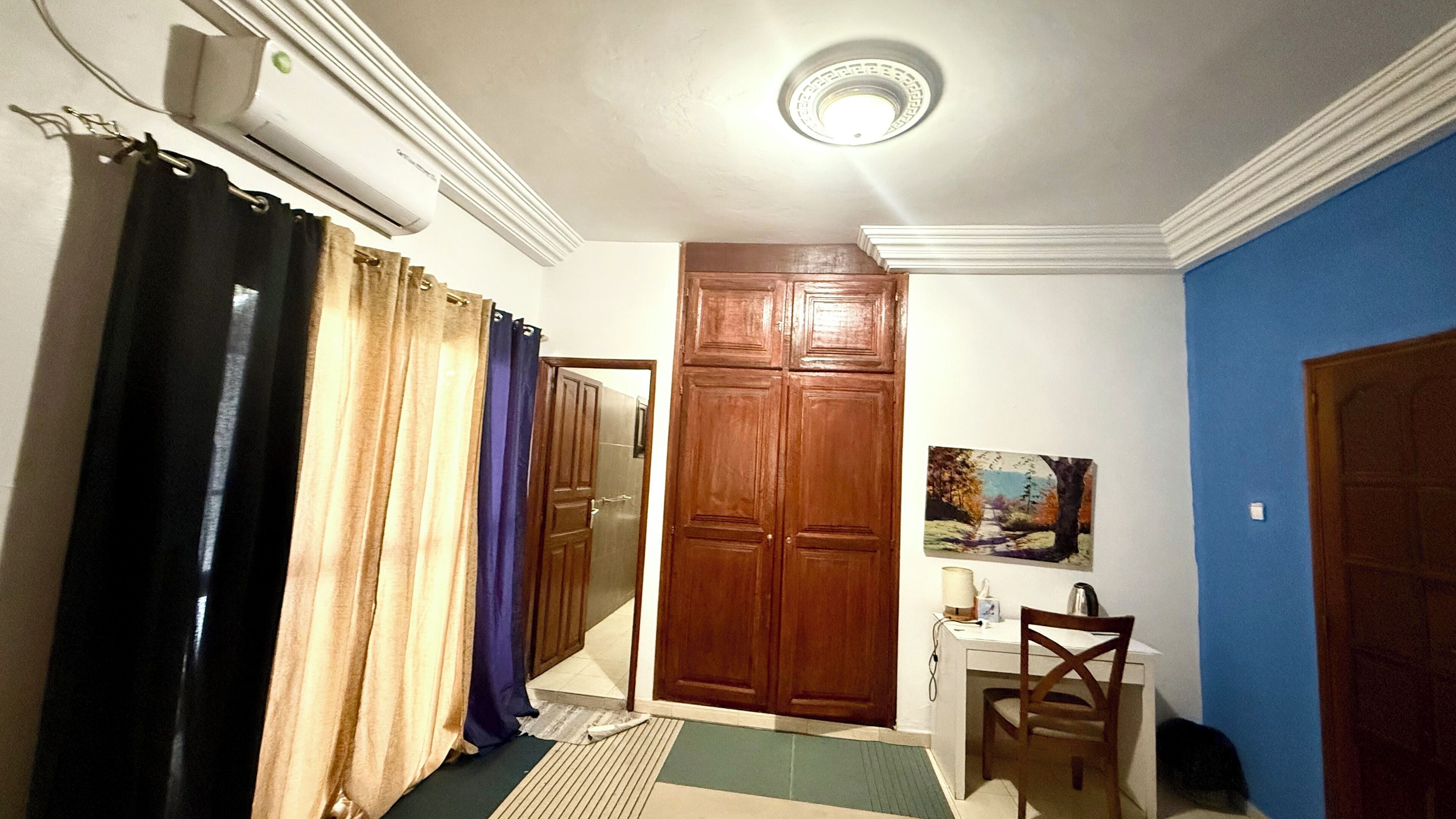 Un pasillo con una puerta de madera, un escritorio con una silla y un cuadro en la pared.