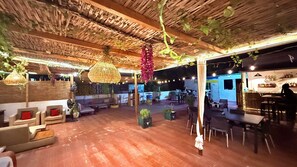 An indoor space with wooden ceiling, hanging plants, and seating arrangements. - Villa Jade (Dakar)