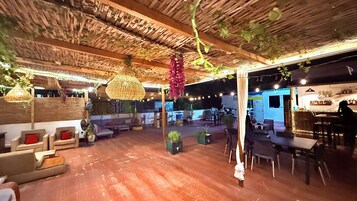 Un espacio interior con techo de madera, plantas colgantes y arreglos de asientos.