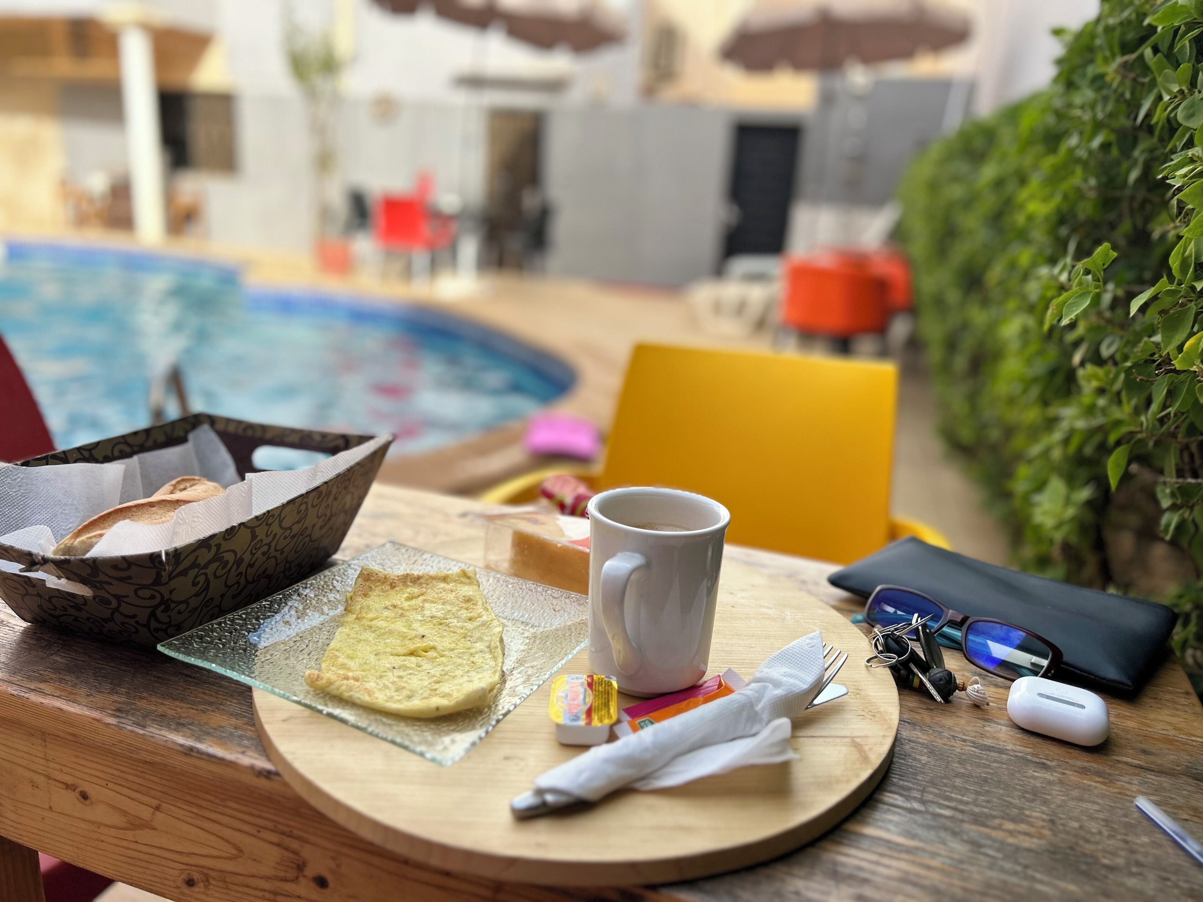 Ein Tablett mit Toast, einer Tasse und einem Servietten auf einem Holztisch in der Nähe eines Pools.