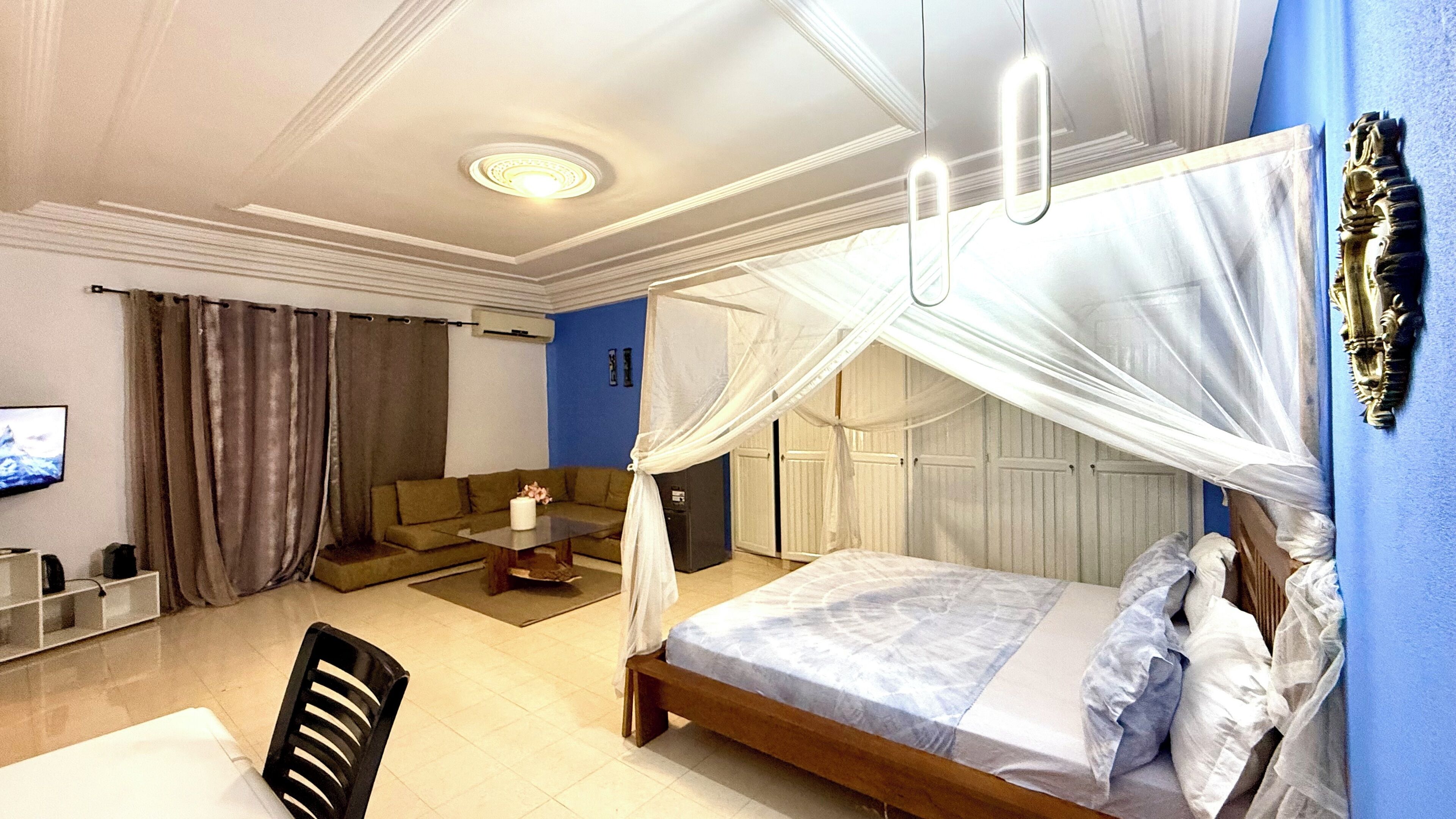 A bedroom with a canopy bed, a sofa, a coffee table, and a TV.