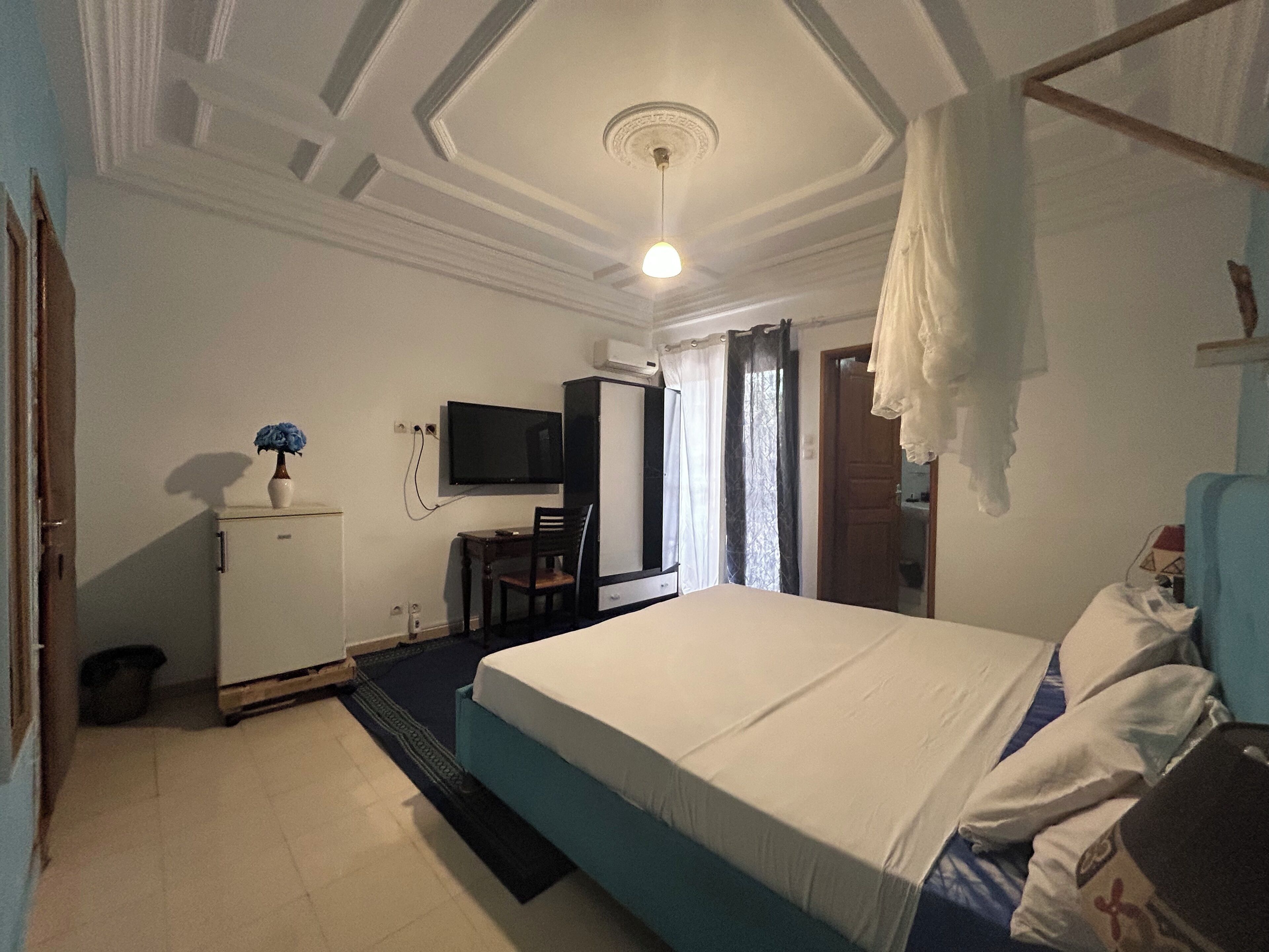 A bedroom with a bed, a desk, a television, and a wardrobe.