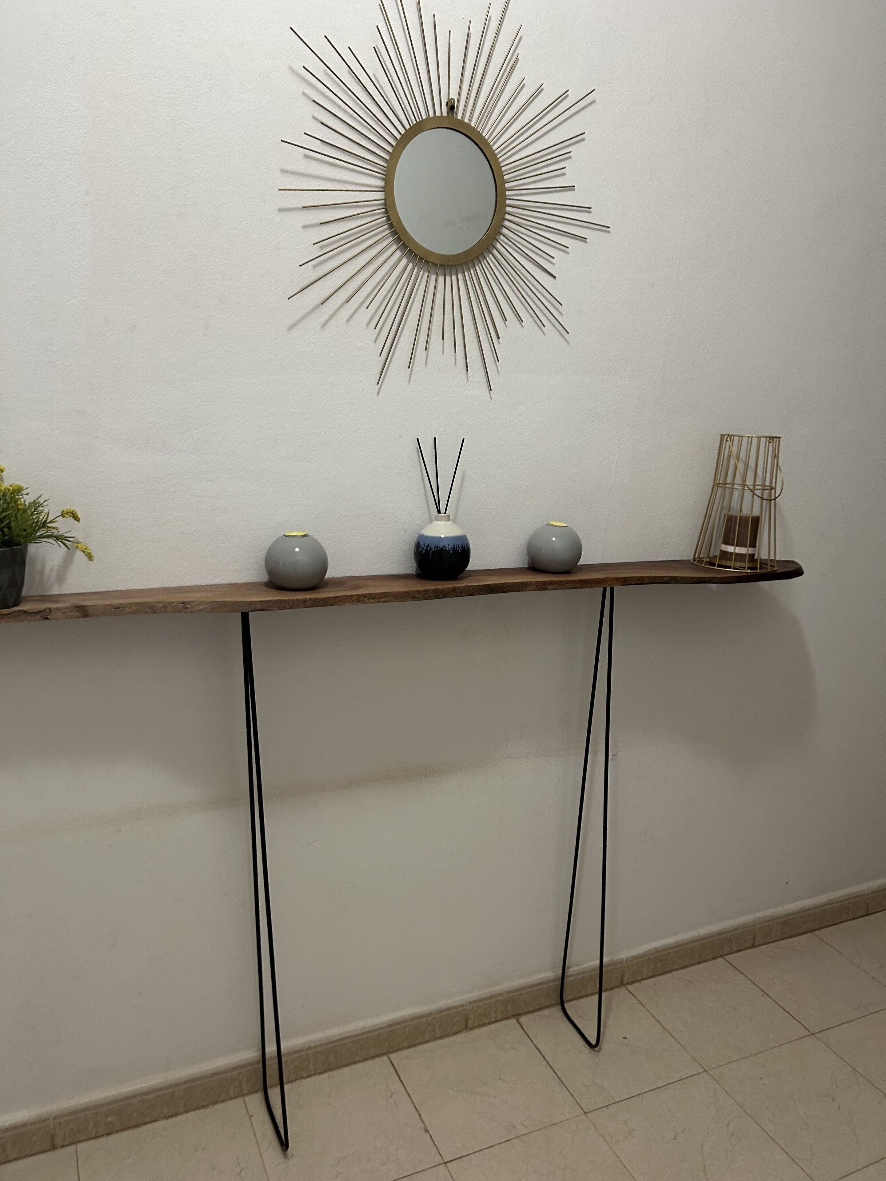 A wooden console table with a mirror and three decorative vases against a white wall.