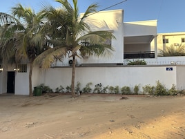 Un edificio moderno con fachada blanca, unidad de aire acondicionado visible y un letrero que indica