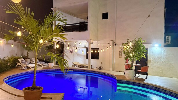 Una piscina all'aperto con lettini, piante in vaso e luci decorative.