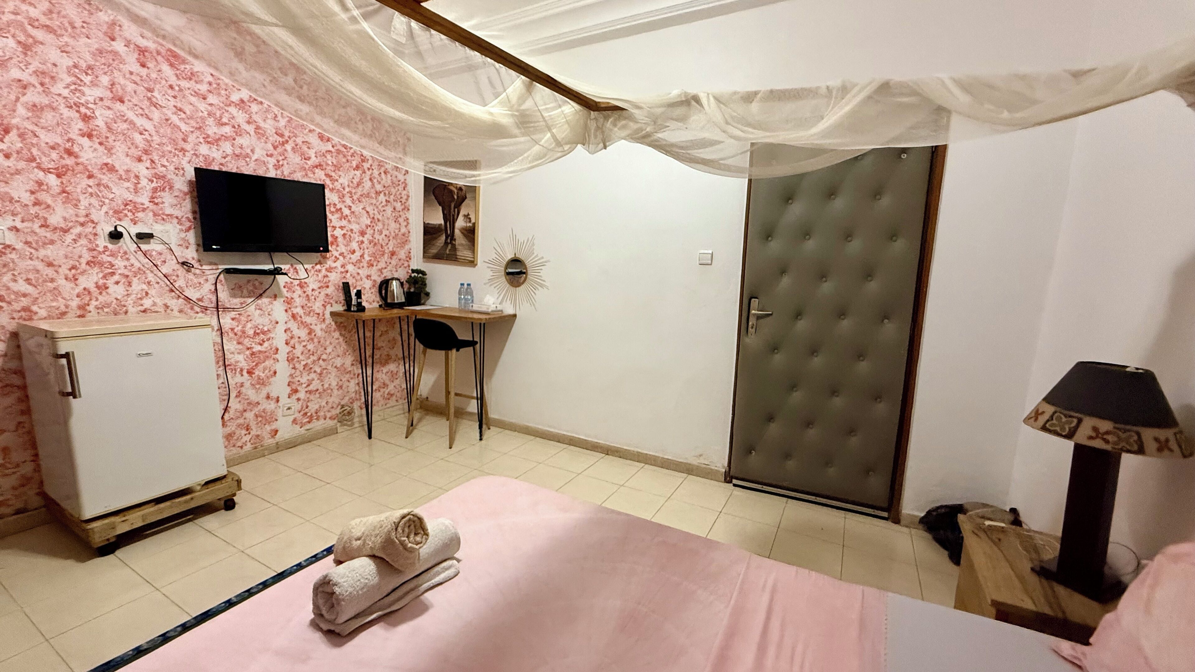 Une chambre à coucher comprenant un lit, un bureau, une armoire, une télévision et une lampe.
