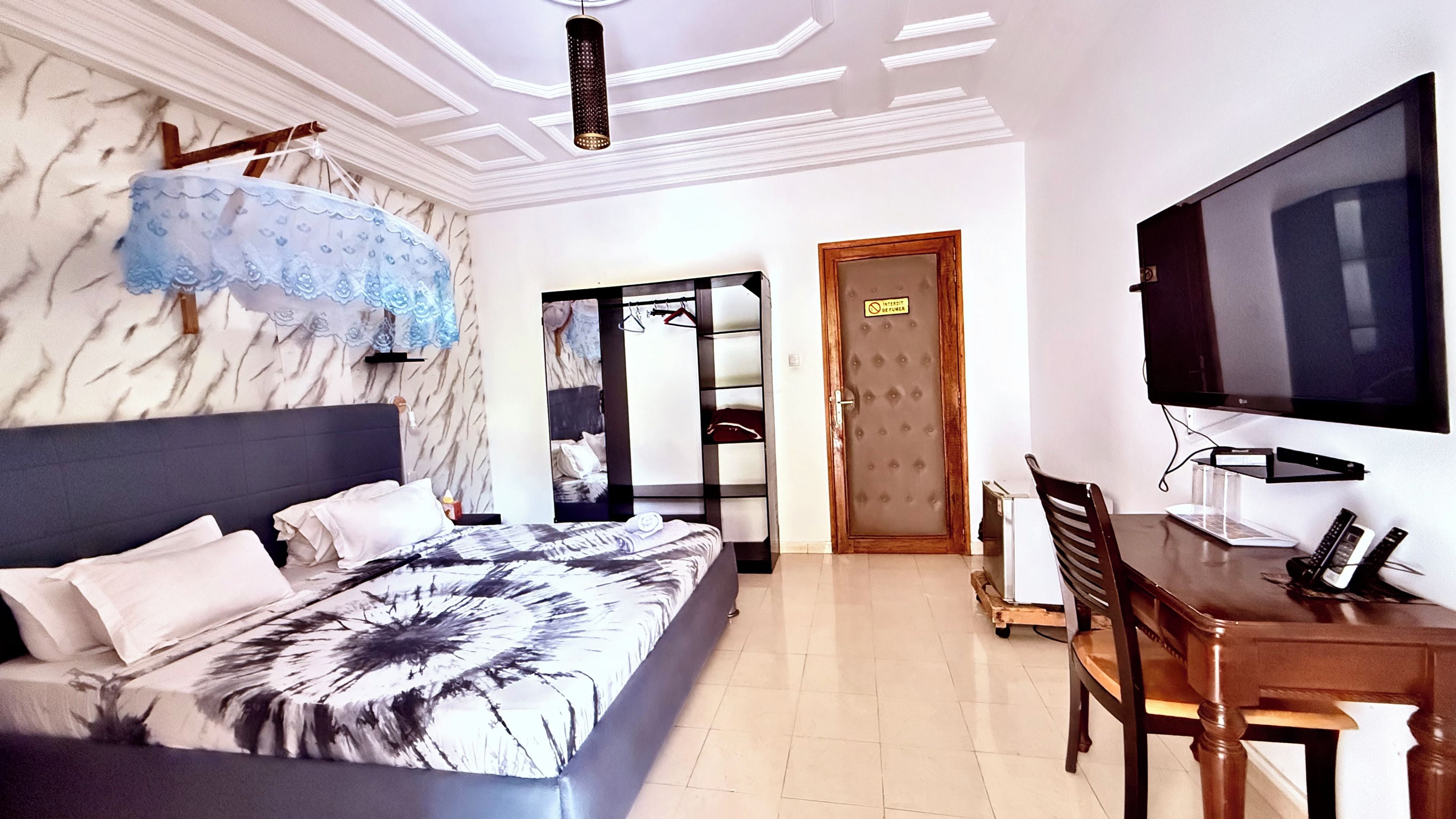 Une chambre d’hôtel équipée d’un lit, d’un bureau, d’une télévision et d’une armoire.