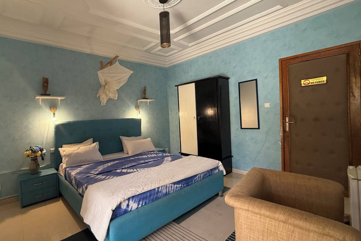 A bedroom with a bed, bedside tables, a chair, a wardrobe, and a door.
