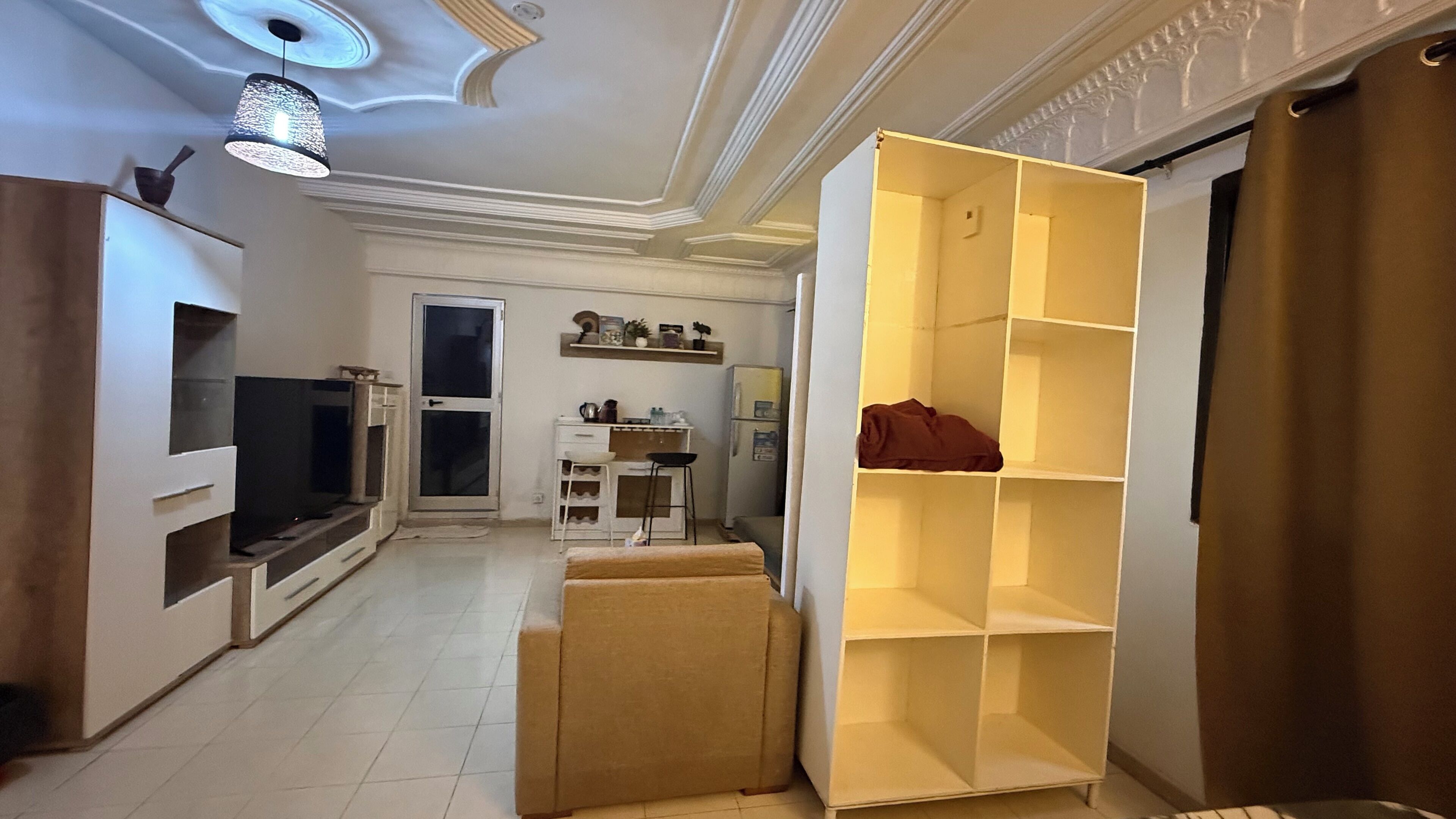 Una sala de estar con televisor, sofá y una amplia estantería.