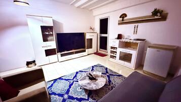 A living room with a flat-screen TV, a sofa, a coffee table, and a patterned rug.